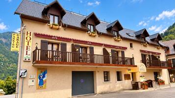 Een hotel in traditionele Alpenarchitectuur, met een balkon met houten leuningen en een bord dat een garage en parkeergelegenheid aangeeft.