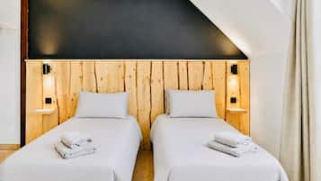 Habitación doble con dos camas, paredes de paneles de madera y lámparas de noche.