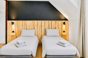 A double room with two beds, wooden panel walls, and bedside lamps.