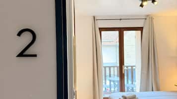 A hotel room with a bed, a balcony, and a number '2' on the wall.
