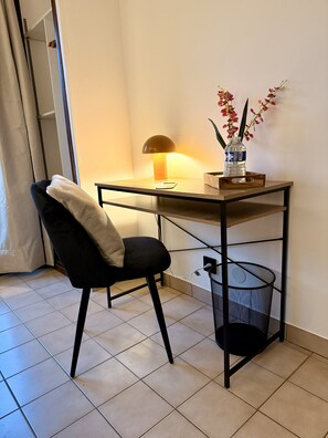 A small, modern room with a desk, chair, lamp, and a water bottle on the table.