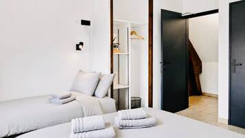 A modern hotel room with two beds, a wardrobe, and a staircase.