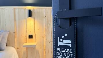 Une chambre d’hôtel avec un lit, une table de chevet et un panneau fixé au mur, orné d’une icône représentant un lit et d’un texte.