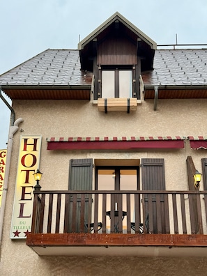 Un hotel con balcón, cartel y tejado de tejas.