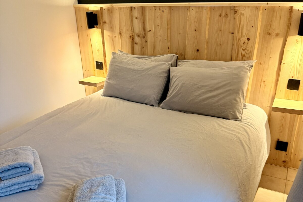 A bed with a wooden headboard, two pillows, and two bedside lamps.