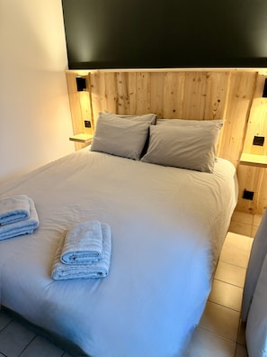 A bed with a wooden headboard, two pillows, and two bedside lamps.