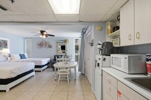 A compact hotel room with a bed, a small dining table with chairs, a kitchenette with a microwave, and a ceiling fan. - Long Beach Resort Beachfront Studio with Ocean View Balcony, Sleeps 4, Tower 1 (Panama City Beach)