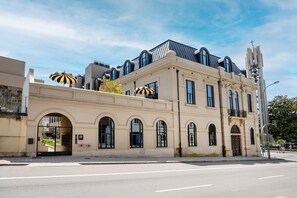 Ein Gebäude mit einer klassischen Fassade, großen Bogenfenstern und einem modernen Anbau mit einem geneigten Dach.