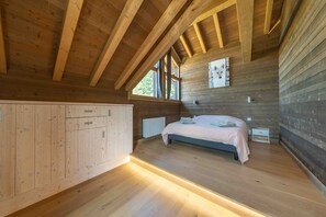 A wooden interior with a bed, a radiator, and a window. - Chalet 'L'Alpage' with Mountain View, Sauna and Jacuzzi (Gérardmer)