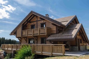 A wooden cabin with a balcony, a covered deck, and a sloped roof. - Chalet 'L'Alpage' with Mountain View, Sauna and Jacuzzi (Gérardmer)