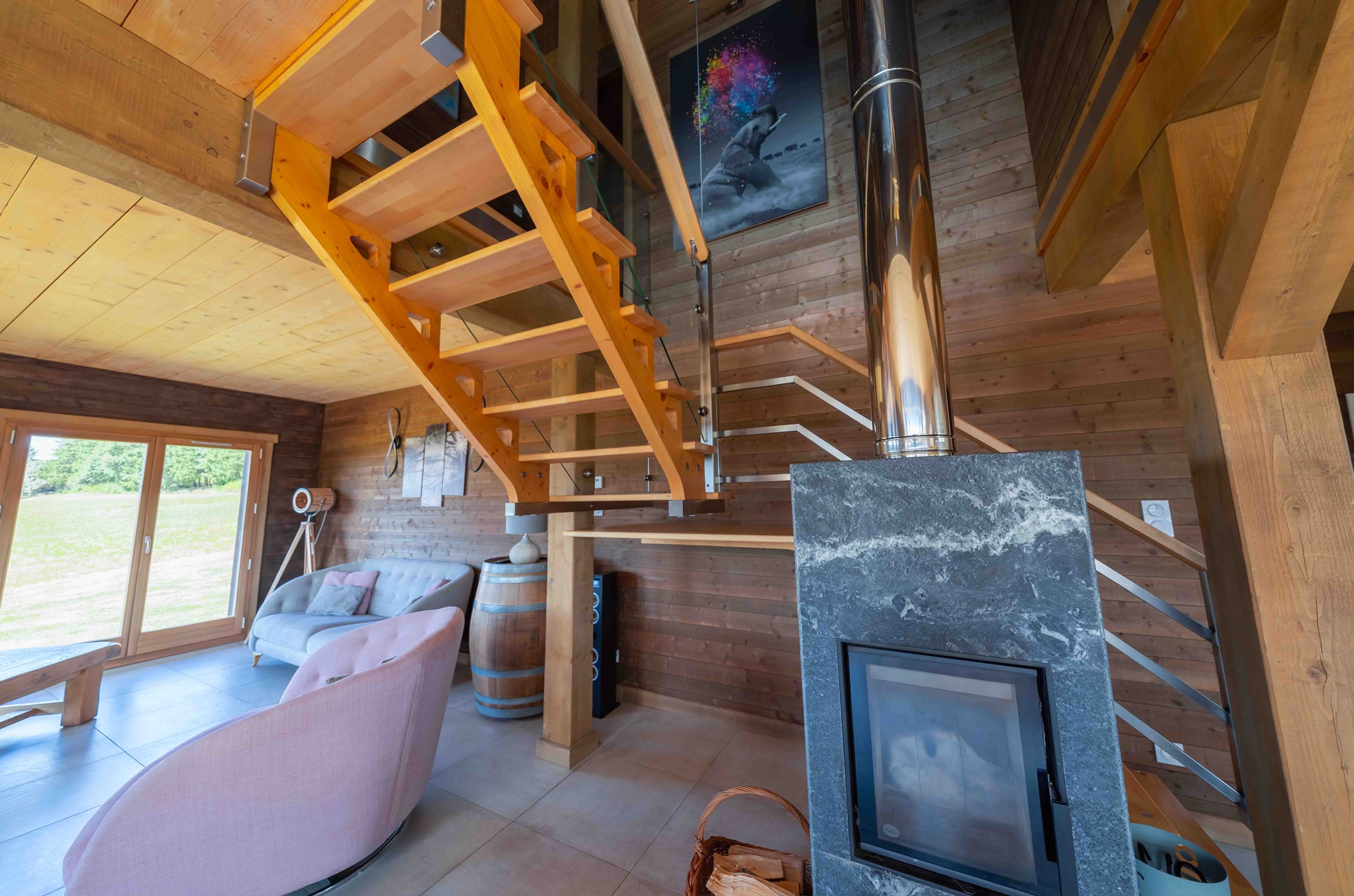 A wooden interior with a fireplace, a sofa, and a wooden staircase.
