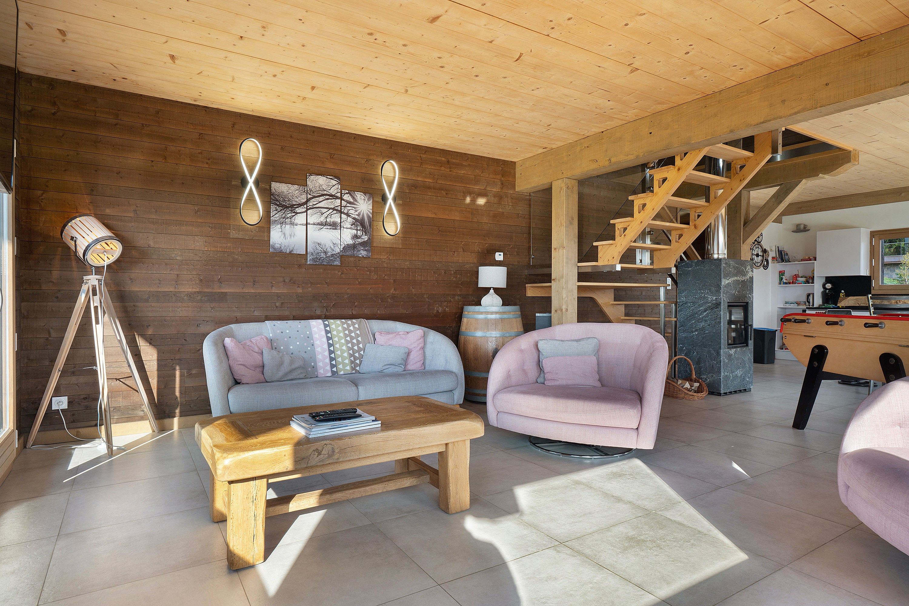 A modern living room with a wooden ceiling, a sofa, a coffee table, and a staircase.