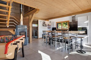 A modern kitchen with a foosball table, bar stools, and a large window. - Chalet 'L'Alpage' with Mountain View, Sauna and Jacuzzi (Gérardmer)