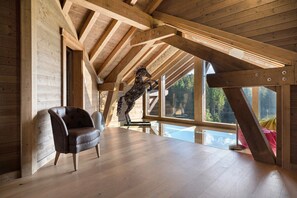 A spacious room with wooden beams, a leather chair, and a sculpture.