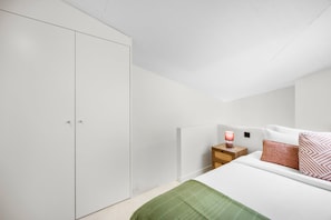 Ein Schlafzimmer mit einem Bett, einem Nachttisch, einer Lampe und einem Kleiderschrank.