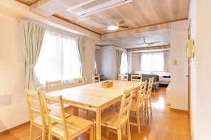 A spacious room with a wooden dining table and chairs, a ceiling fan, and a bed with a headboard. - GrandHOUSE SHINJUKU 301 (Nakano City)