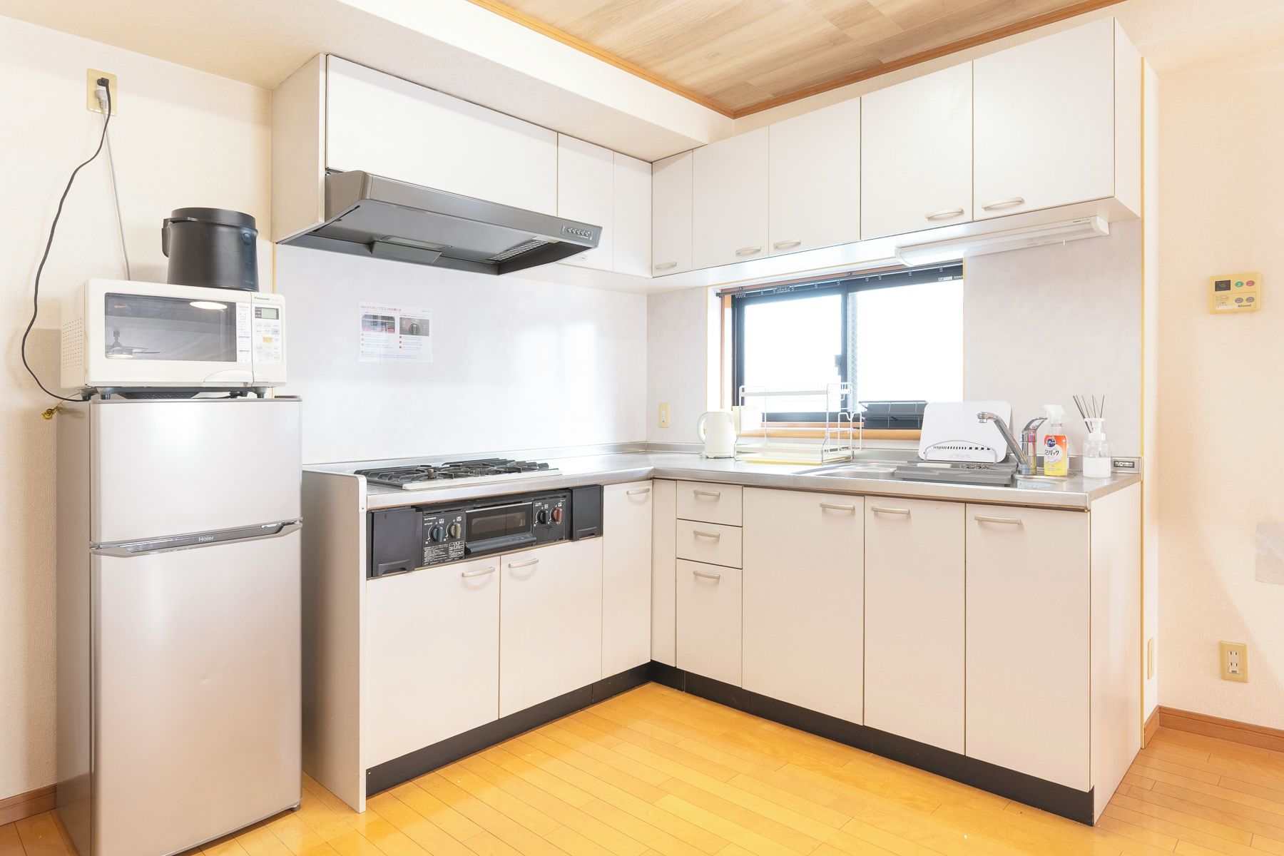 Cozinha compacta com micro-ondas, fogão e forno. Uma janela oferece iluminação natural.