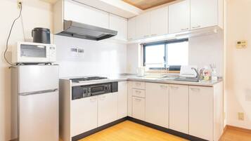 Cozinha compacta com micro-ondas, fogão e forno. Uma janela oferece iluminação natural.
