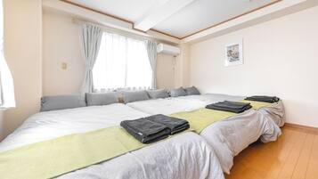 Quarto de hotel com uma cama grande, duas mesas de cabeceira, uma janela com cortinas, um aparelho de ar condicionado e um quadro na parede.