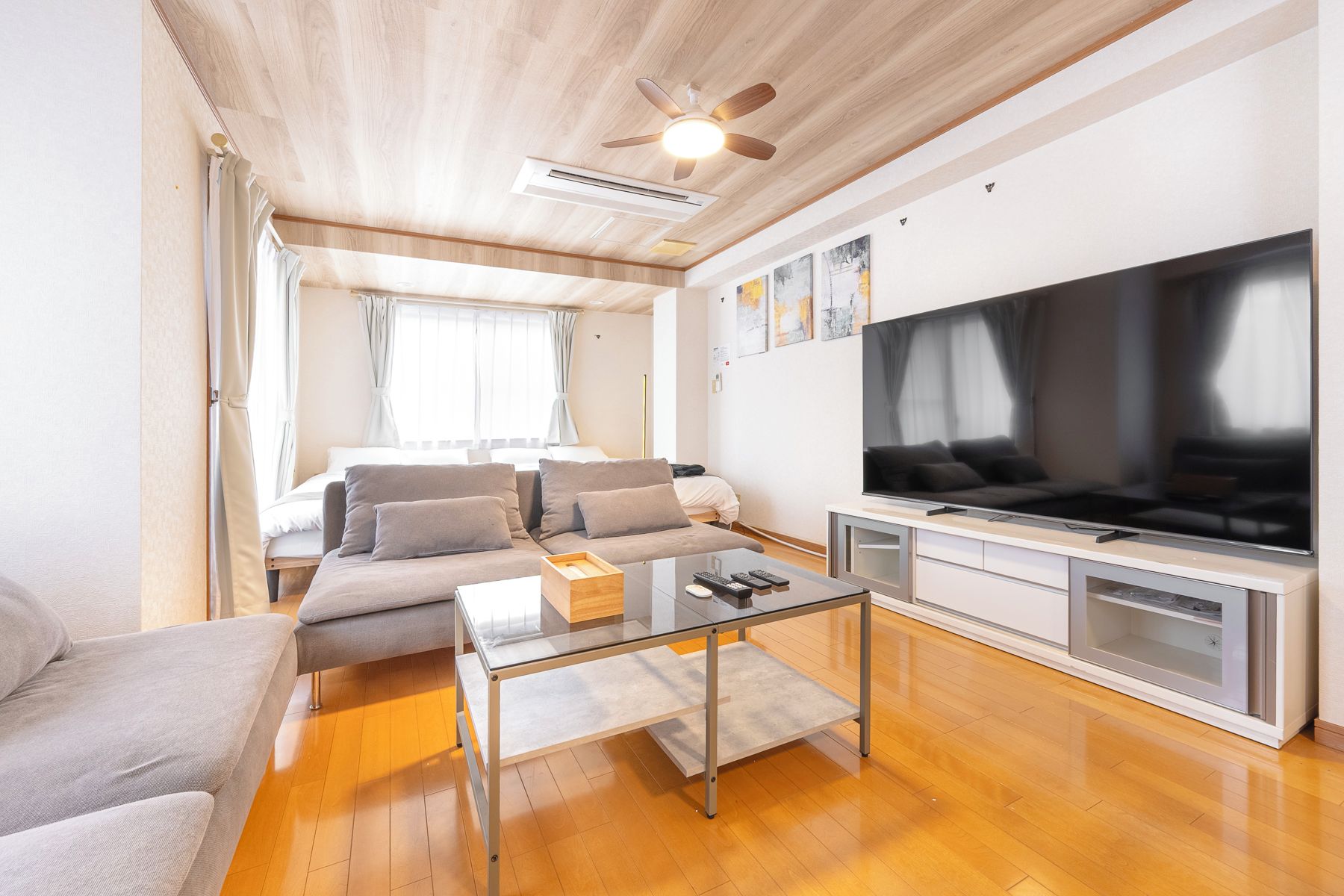 Un salon moderne avec un canapé, une table basse, un téléviseur et un ventilateur de plafond.