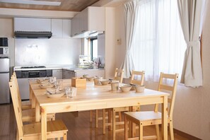 A modern kitchen with wooden cabinets, a built-in oven, and a dining area with a wooden table and chairs.