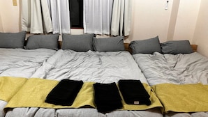 A hotel room with a large bed, multiple pillows, a blanket, and a bedside table with a lamp. - GrandHOUSE SHINJUKU 301 (Nakano City)
