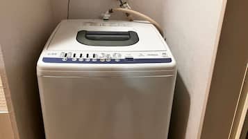 Máquina de lavar roupa compacta, branca e fixada na parede, com painel de controle e uma mangueira.
