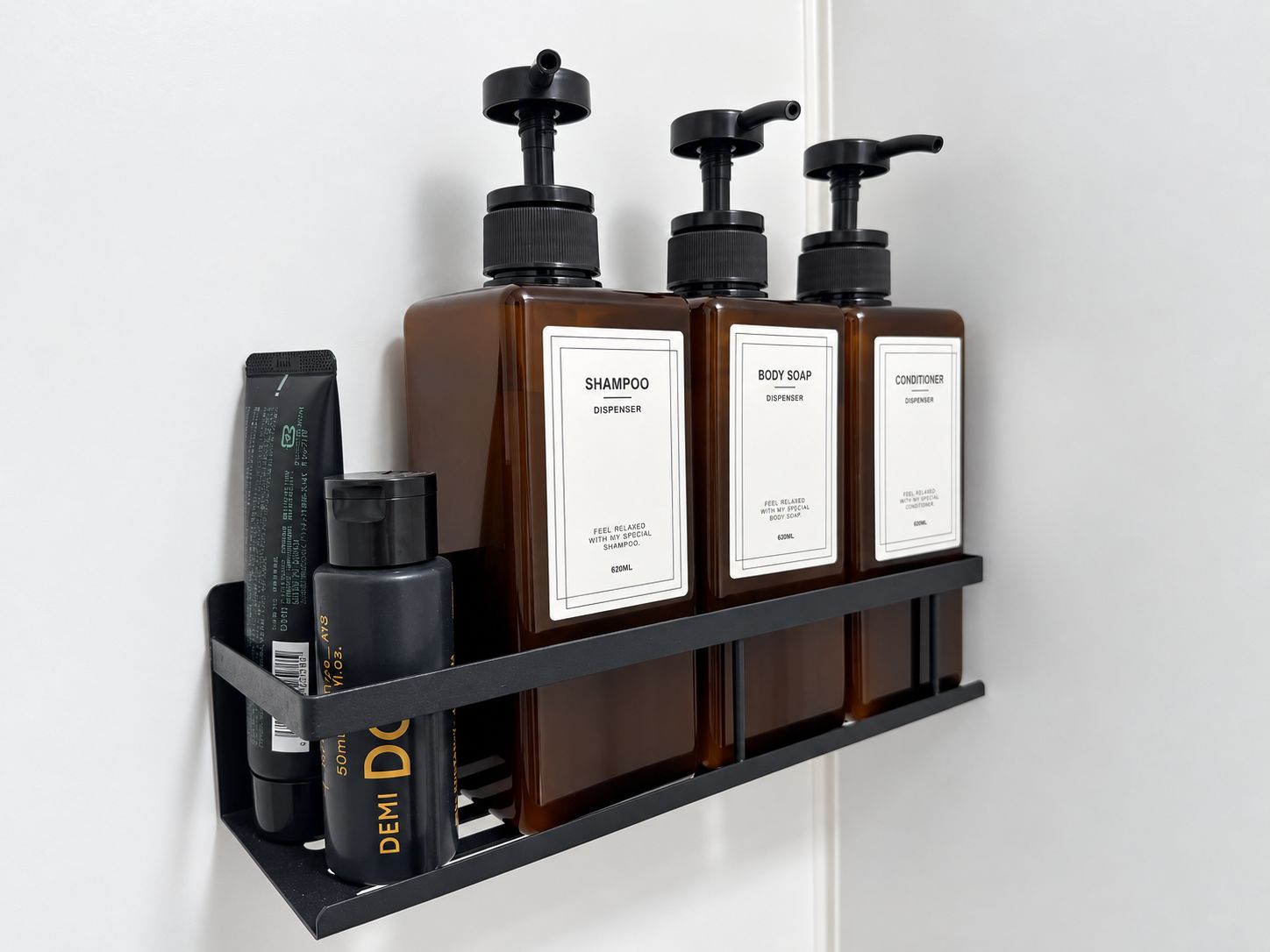 Prateleira na parede com três frascos de shampoo, sabonete líquido e condicionador.