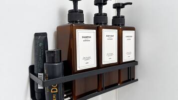 Prateleira na parede com três frascos de shampoo, sabonete líquido e condicionador.