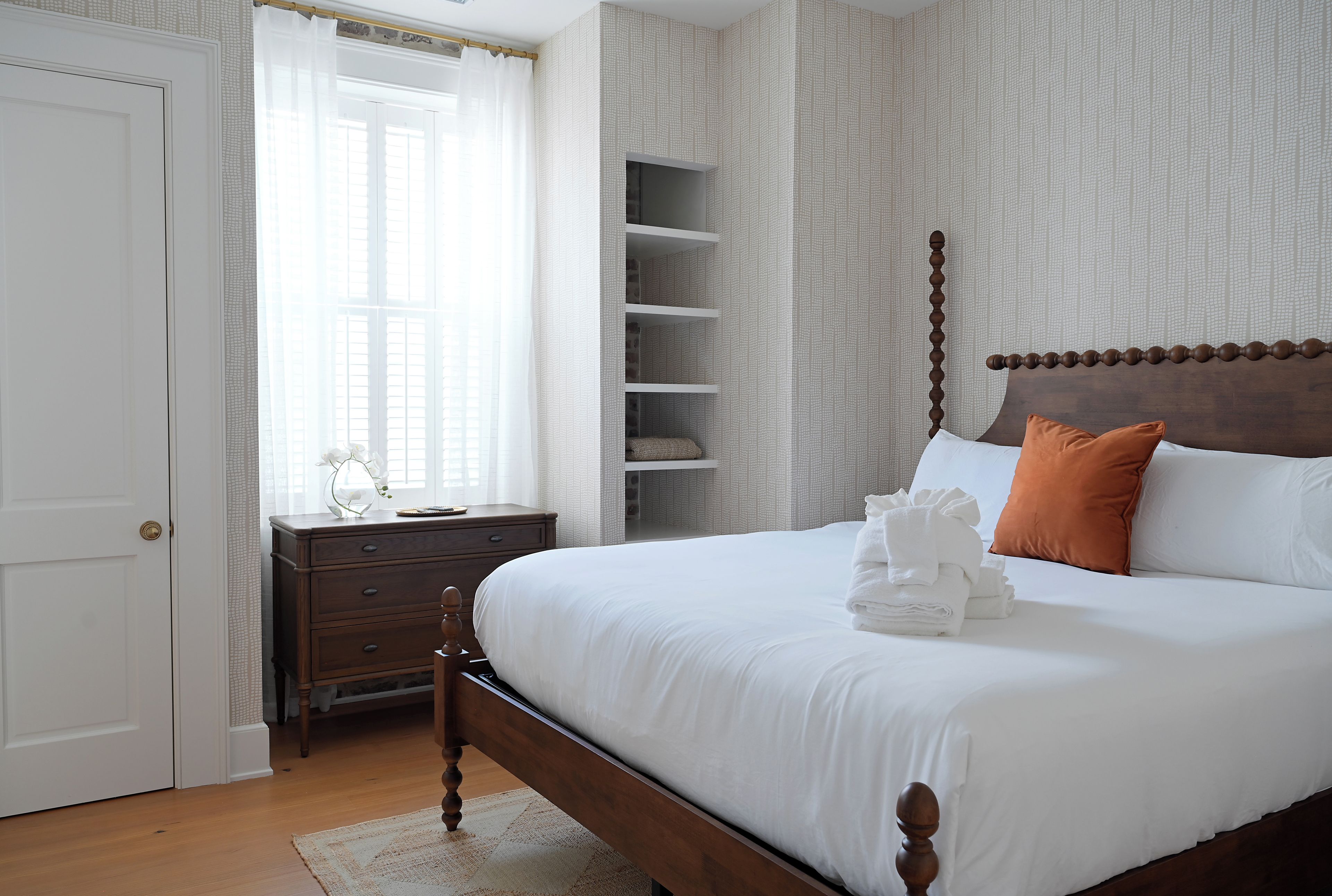 Un dormitorio ordenado con una cama de madera, una mesita de noche y un mueble empotrado con estanterías.