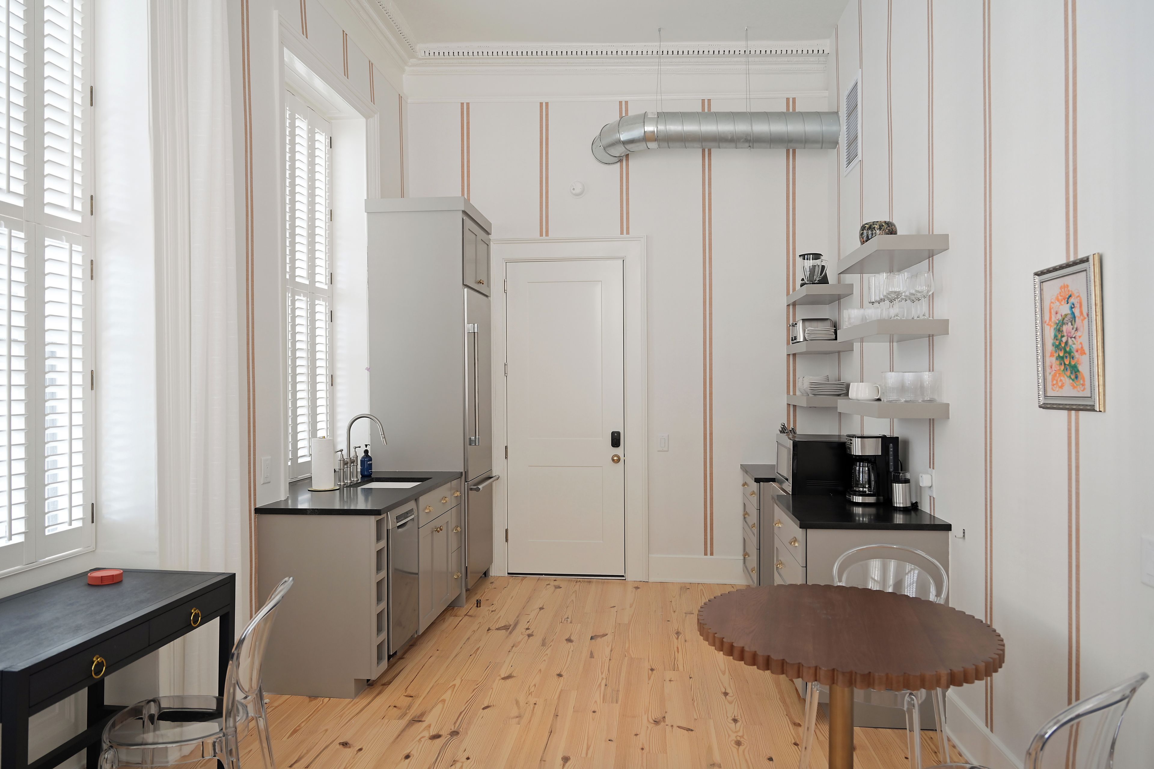 Una cocina funcional con refrigerador, pileta y comedor con mesa y sillas.