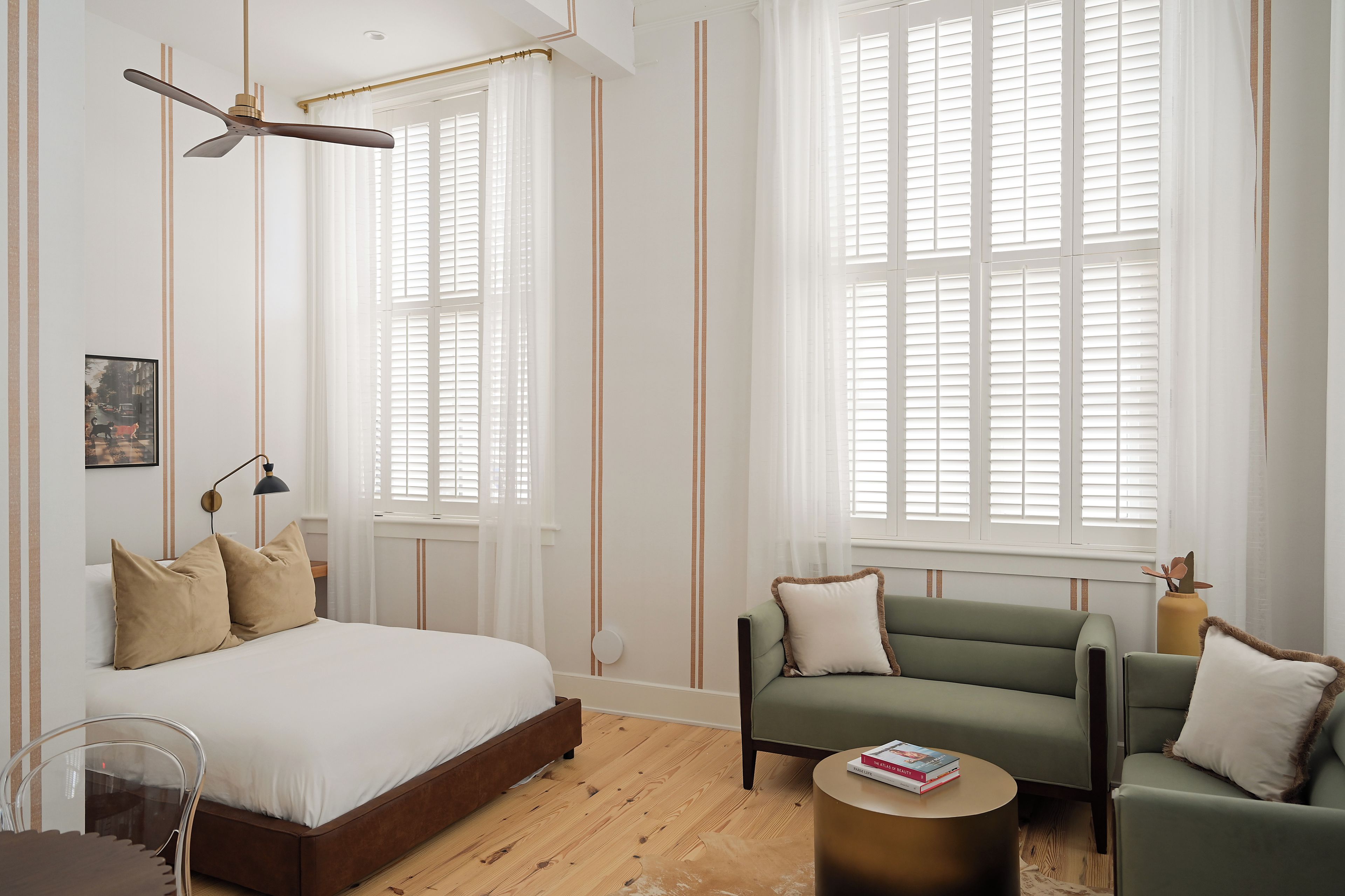 Un dormitorio moderno con una cama, un sofá verde, una mesita de centro redonda y un ventilador de techo.