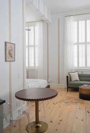 Una habitación con una mesa redonda, un sofá y una ventana con persianas.