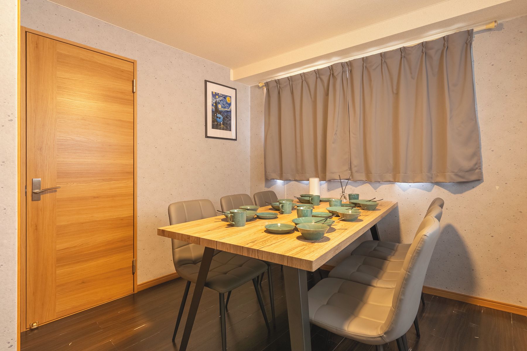Un coin repas avec une table en bois, quatre chaises et une œuvre d’art encadrée accrochée au mur.