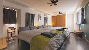 A hotel room with a large bed, a wooden chair, a desk, and a ceiling fan.