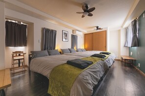 A hotel room with a large bed, a wooden chair, a desk, and a ceiling fan.
