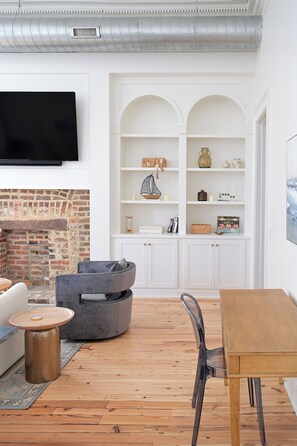 Una sala de estar moderna con chimenea, un televisor de pantalla plana en la pared, una mesa de comedor de madera y una zona de estar confortable.