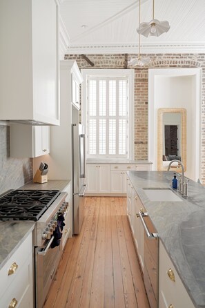 Una cocina moderna con armarios blancos, suelo de madera y pared de ladrillo.