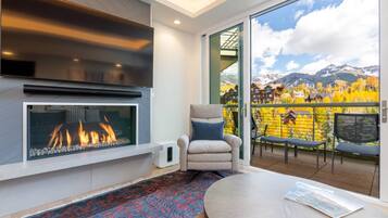 Un interior moderno con chimenea, un sillón cómodo y un balcón con vistas panorámicas a la montaña.