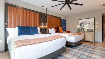 A hotel room with two beds, a ceiling fan, a wall-mounted light fixture, and a framed picture on the wall.