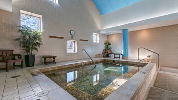 A swimming pool with a tiled floor, a clock on the wall, and a blue ceiling.