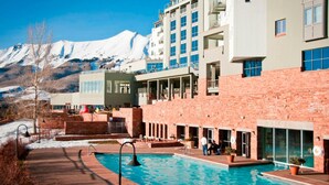Ett hotell med pool, utsikt över bergen och en fasad av tegel.
