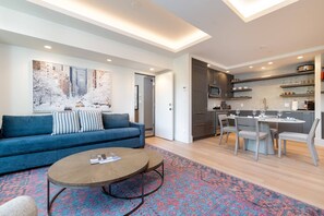 A modern living room with a blue sofa, a coffee table, and a patterned rug.