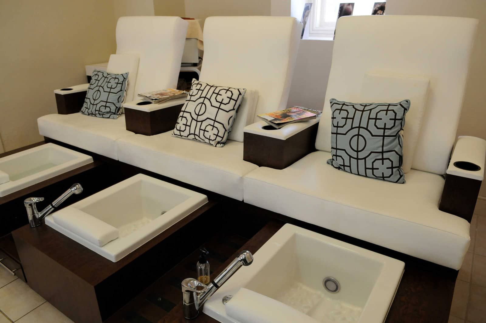 A hotel bathroom with multiple sinks, a sofa with patterned cushions, and a trash bin.
