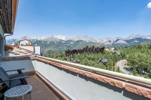 Ein Balkon mit Blick auf ein Gebirge und eine Berghütte.