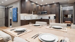 Une cuisine moderne avec des meubles en bois foncé, un four à micro-ondes en acier inoxydable et un dosseret de carrelage blanc.