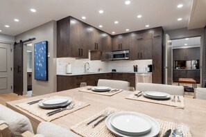 Cozinha moderna com armários de madeira escura, micro-ondas de aço inoxidável e painel de azulejos branco.