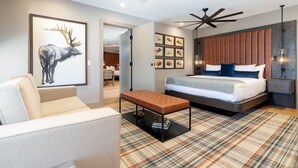 Une chambre à coucher moderne avec un lit, un ventilateur de plafond, une œuvre d’art représentant un élan accrochée au mur et un tapis à motifs.
