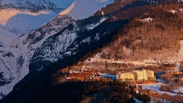A mountain resort with a large lodge and cabins, surrounded by snow-covered peaks and forested slopes.