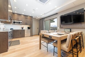 A modern kitchen with wooden cabinets, a built-in microwave, and a dining area with a table and chairs.